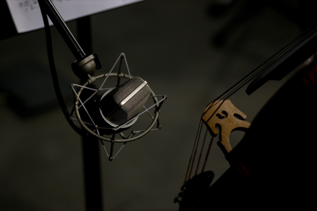 A studio microphone poised beside the scroll of a double bass